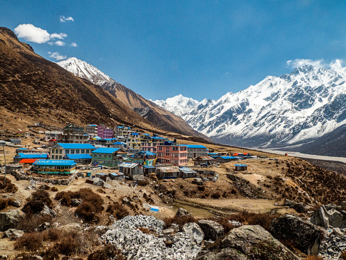 a village in the mountains with snow capped mountains in the background