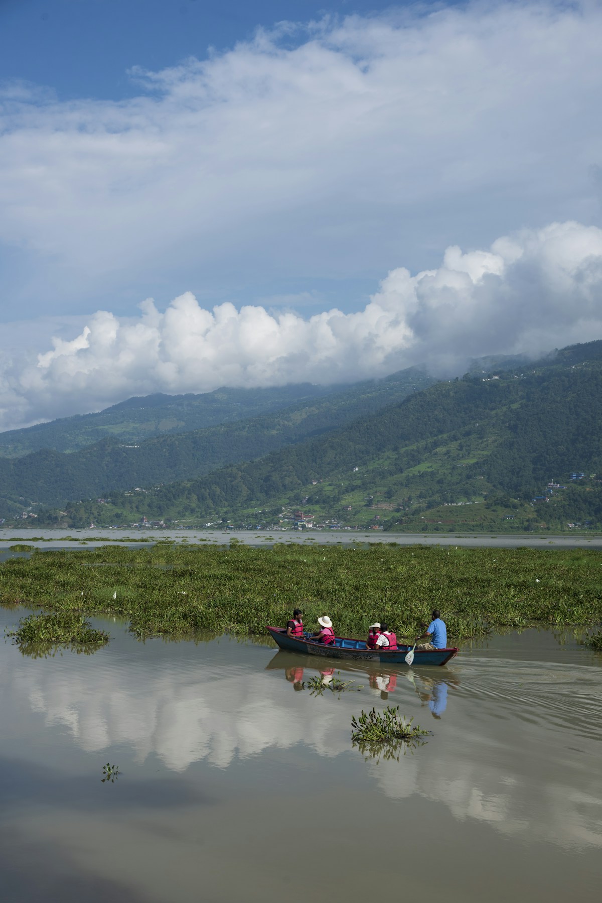 People in a boat on a lake with mountains.